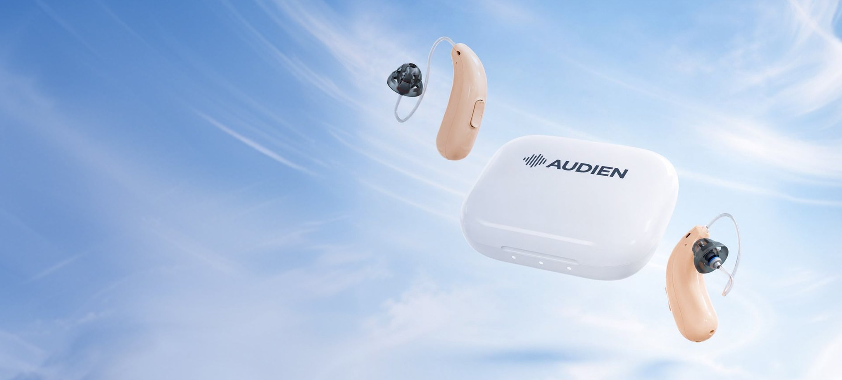 Audien wireless hearing aids and their charging case floating against a bright blue sky background with wispy clouds.